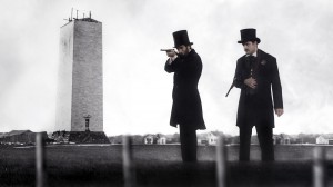 (l-r) President Abraham Lincoln (Tom Amandes) test fires Spencer rifles with U.S. Marshal Ward Hill Lamon (Lea Coco) in front of the unfinished Washington Monument at the height of the Civil War in "Saving Lincoln." ©Saving Lincoln, LLC.