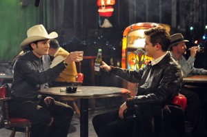 HANK (Henry Thomas) and SILAS (Jesse James) share a New Year’s Eve toast at Dirty John’s Bar in "THE LAST RIDE." ©Live Bait Productions/Mozark Productions